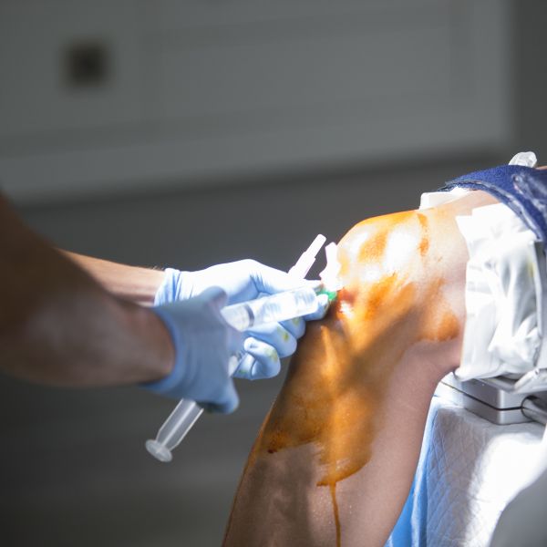 a doctor applying injection in a patients knee