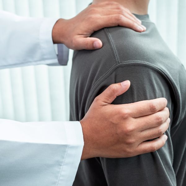 A doctor examining shoulder of a male person