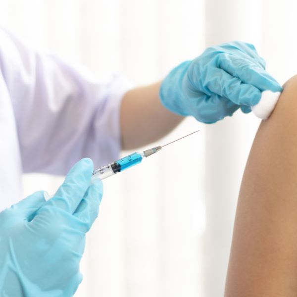 A doctor injecting in shoulder of a patient